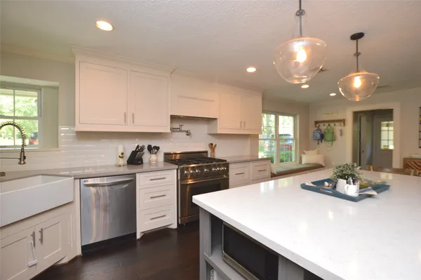 a kitchen with a stove a sink dishwasher a dining table and chairs with wooden floor