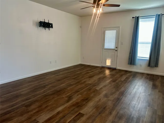a view of an empty room with wooden floor and a window