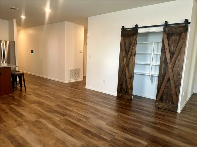 a view of an empty room with wooden floor and a cabinet