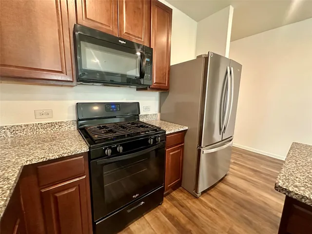 a kitchen with granite countertop a stove microwave and refrigerator