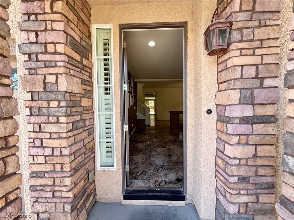 6459 Parrot Ridge Court Las Vegas, NV 89139 - Photo 2 of 23 Enter through a welcoming doorway framed by stacked stone pillars, revealing elegant tile flooring and an inviting interior.