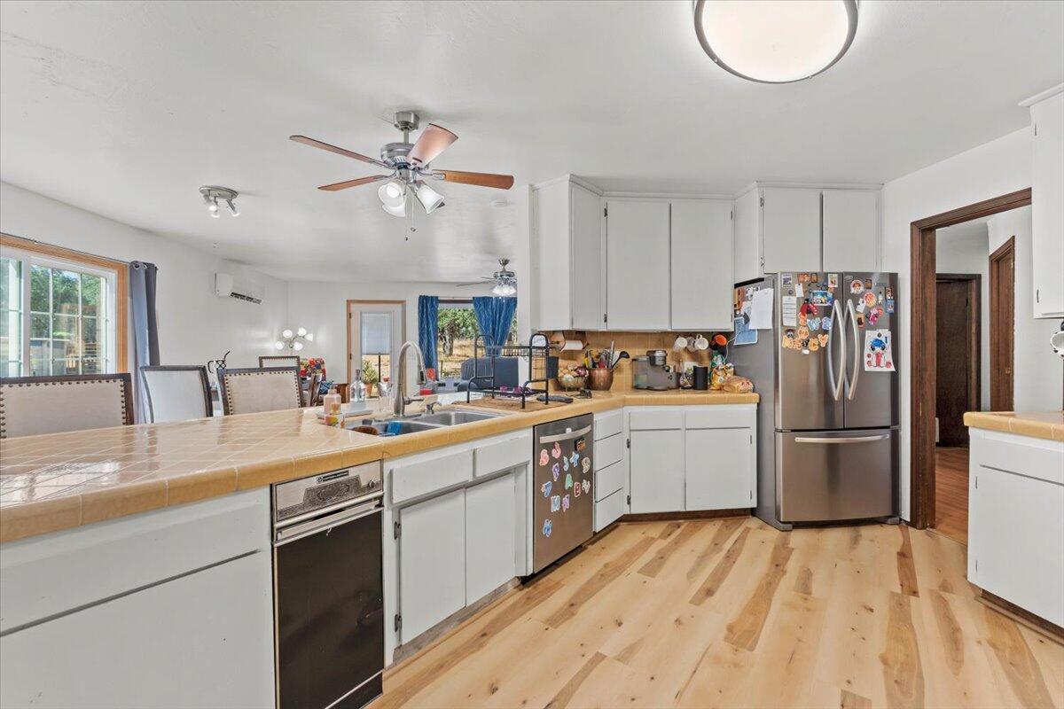 13185 Montecito Road Red Bluff, CA 96080 - Photo 5 of 36 a kitchen with a sink dishwasher a refrigerator and a stove with wooden floor