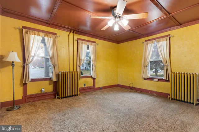 an empty room with chandelier fan and windows