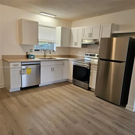 a kitchen with granite countertop a refrigerator stove top oven and sink