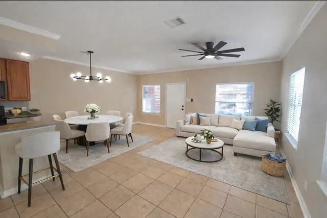 a living room with furniture a chandelier fan and a window