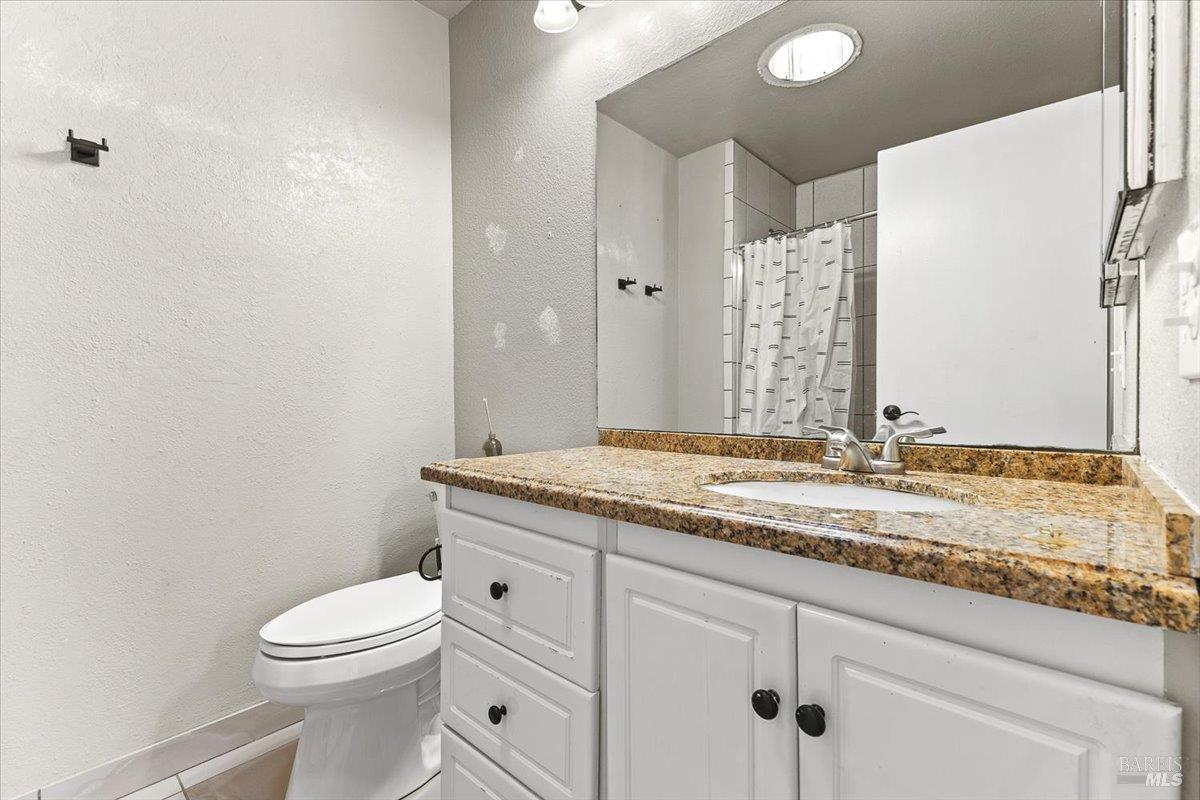 4457 Graywhaler Lane Rohnert Park, CA 94928 - Photo 30 of 51 a bathroom with a granite countertop sink a toilet and a mirror