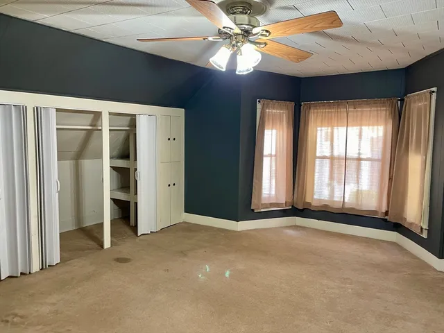 an empty room with windows and fan