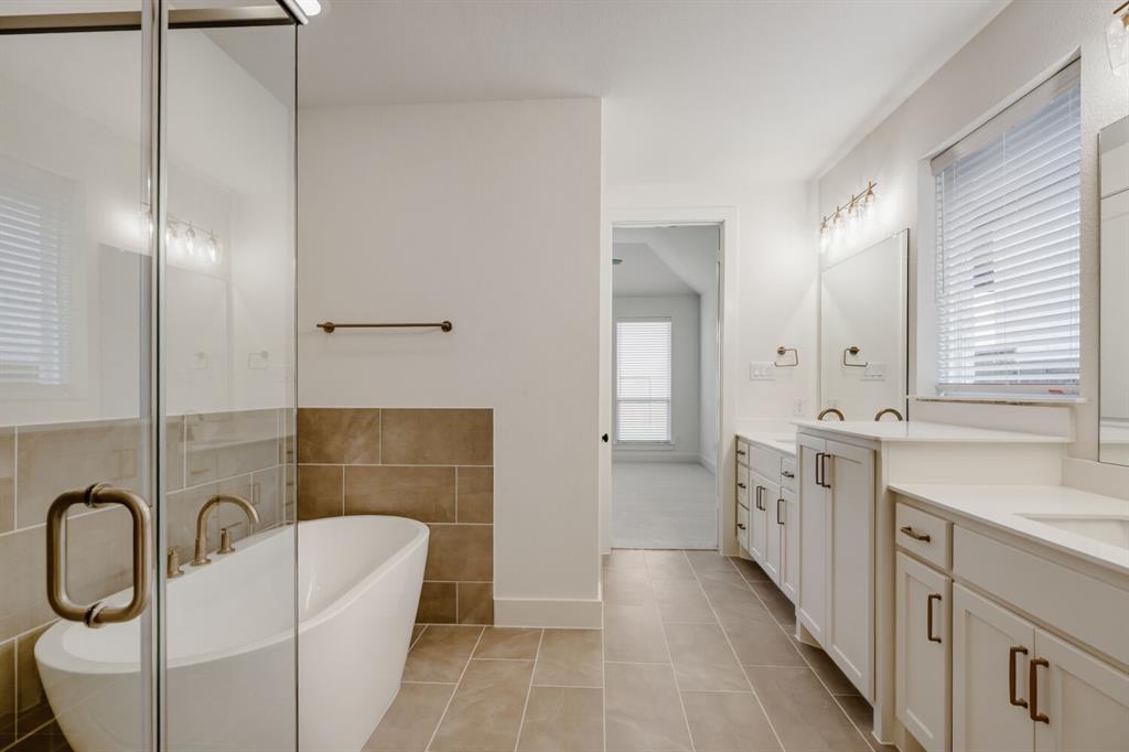 4314 Haley Way Oak Point, TX 75068 - Photo 22 of 28 Bathroom featuring a freestanding tub, glass-enclosed shower, dual vanities with undermount sinks, tile flooring, and white cabinetry with dark hardware