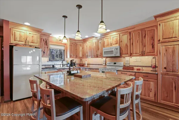 a kitchen with stainless steel appliances granite countertop a stove top oven a sink a counter space and dining table chairs