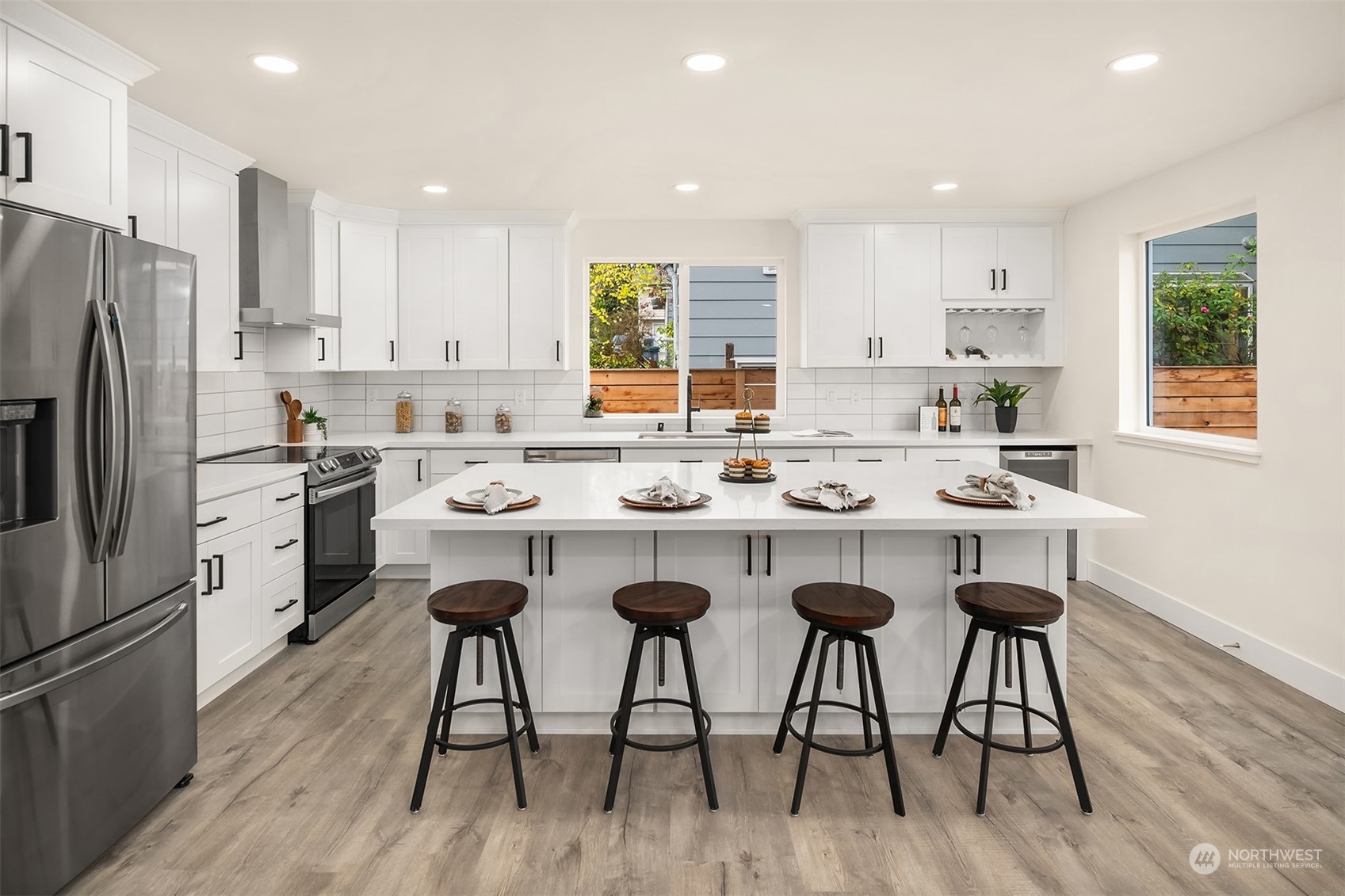 4915 South Genesee Street Seattle, WA 98118 - Photo 2 of 10 a kitchen with stainless steel appliances kitchen island granite countertop a refrigerator a stove a sink and white cabinets with wooden floor