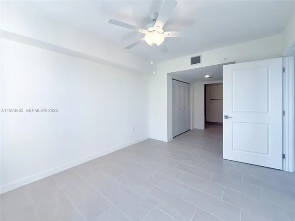 an empty room with a ceiling fan and a window