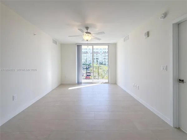 an empty room with windows and chandelier fan