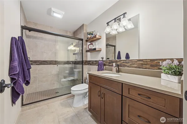 a bathroom with a granite countertop sink a toilet a mirror and shower