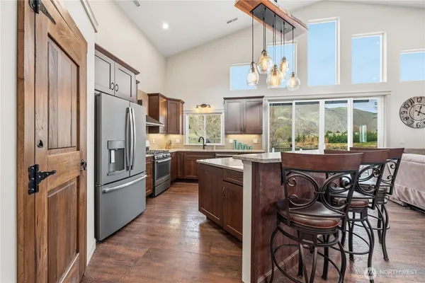 a kitchen with a refrigerator a stove and a dining table with wooden floor