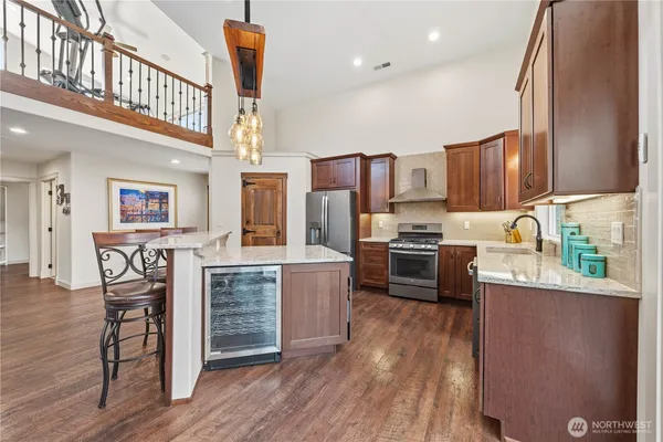 a kitchen with stainless steel appliances a stove a sink dishwasher a refrigerator white cabinets and wooden floor next to a window