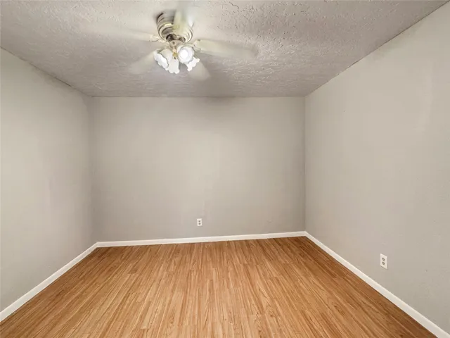 a view of a room with wooden floor and a ceiling fan