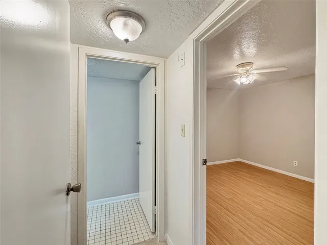 a view of a hallway with a chandelier fan and wooden floor
