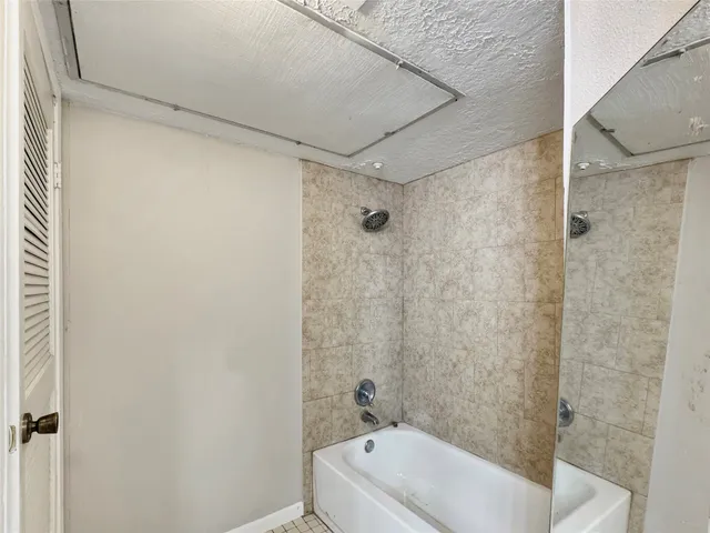 a bathroom with a white bath tub a shower and a sink