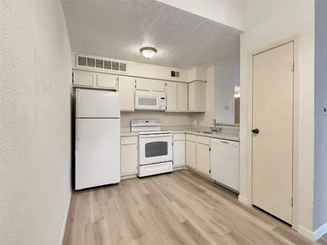 a kitchen with white cabinets and white appliances