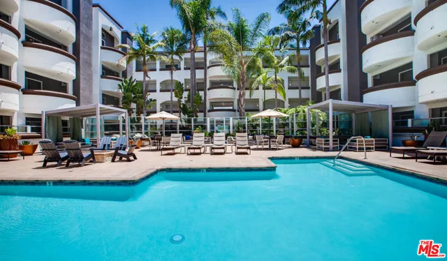 a view of pool with lawn chairs and plants