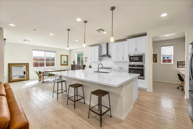 a open kitchen with stainless steel appliances granite countertop a stove a refrigerator a kitchen island a dining table and chairs with wooden floor