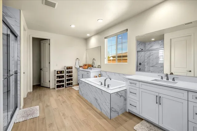 a spacious bathroom with a double vanity sink a mirror and a bathtub