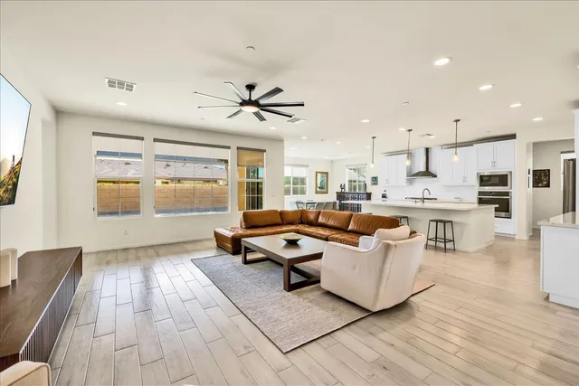 a living room with couches and kitchen view with wooden floor