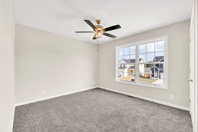 an empty room with windows and ceiling fan