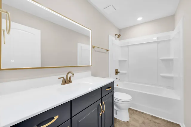 a bathroom with a sink a toilet a mirror and shower