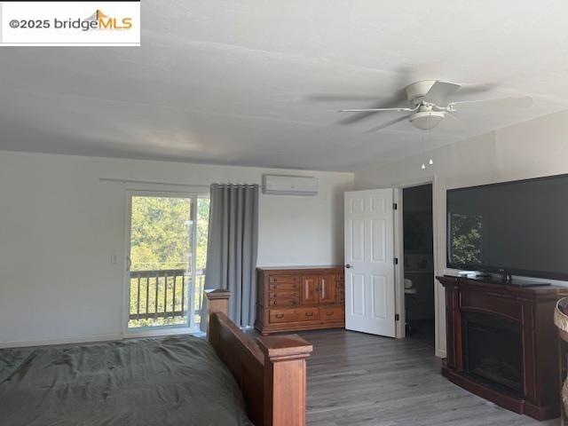 21890 Phoenix Lake Road Sonora, CA 95370 - Photo 8 of 22 Bedroom featuring access to outside, a ceiling fan, wood finished floors, a wall mounted AC, and ensuite bathroom