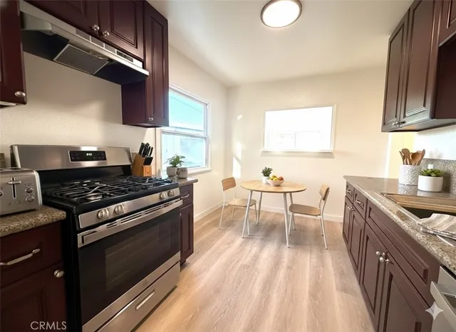 a kitchen with stainless steel appliances granite countertop a stove a sink dishwasher and cabinets with wooden floor