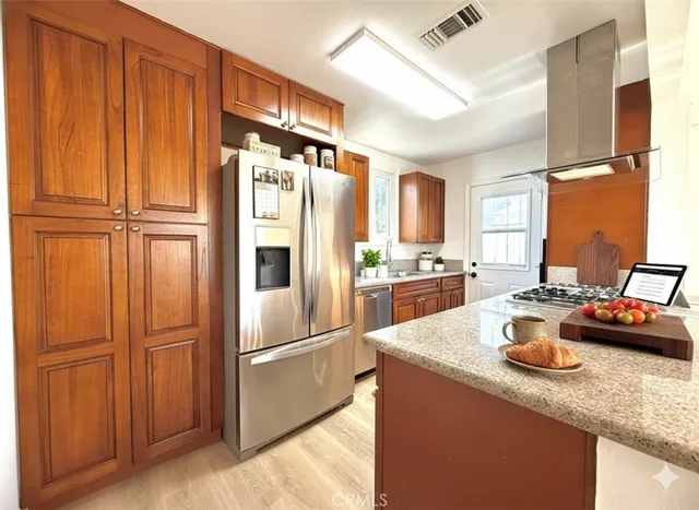 a kitchen with granite countertop stainless steel appliances a refrigerator a sink and cabinets