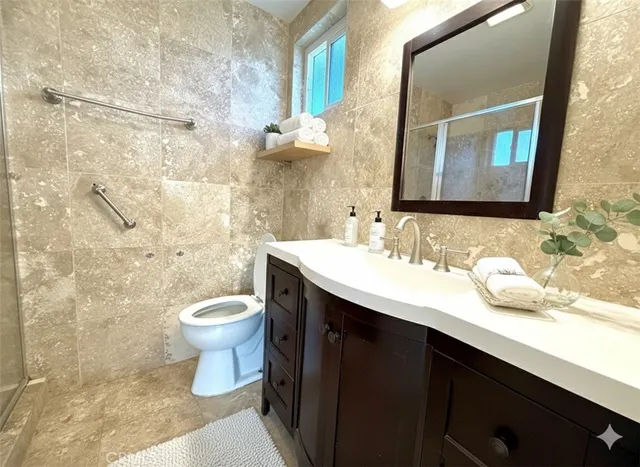 a bathroom with a granite countertop sink toilet and mirror