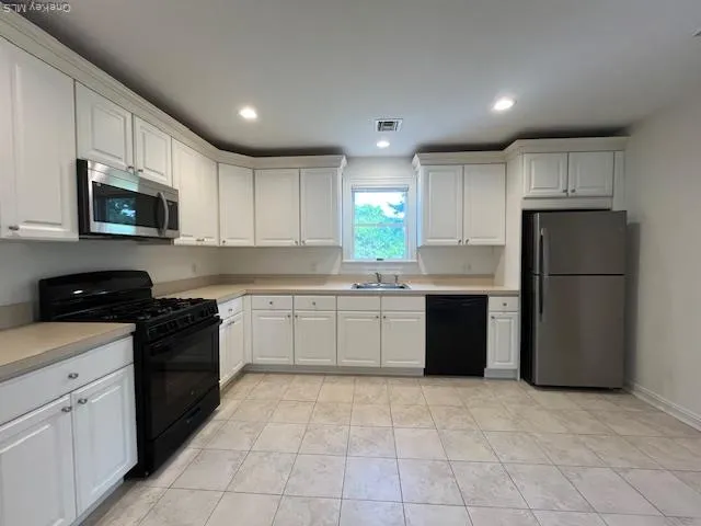 a kitchen with a refrigerator a stove top oven a sink and cabinets
