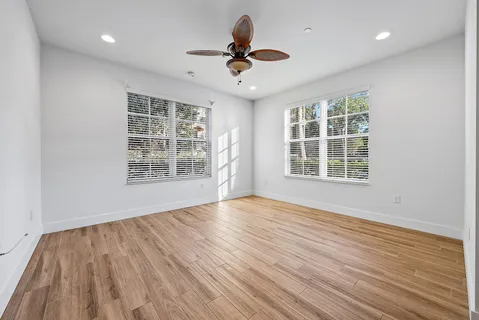 a view of an empty room with wooden floor and a window
