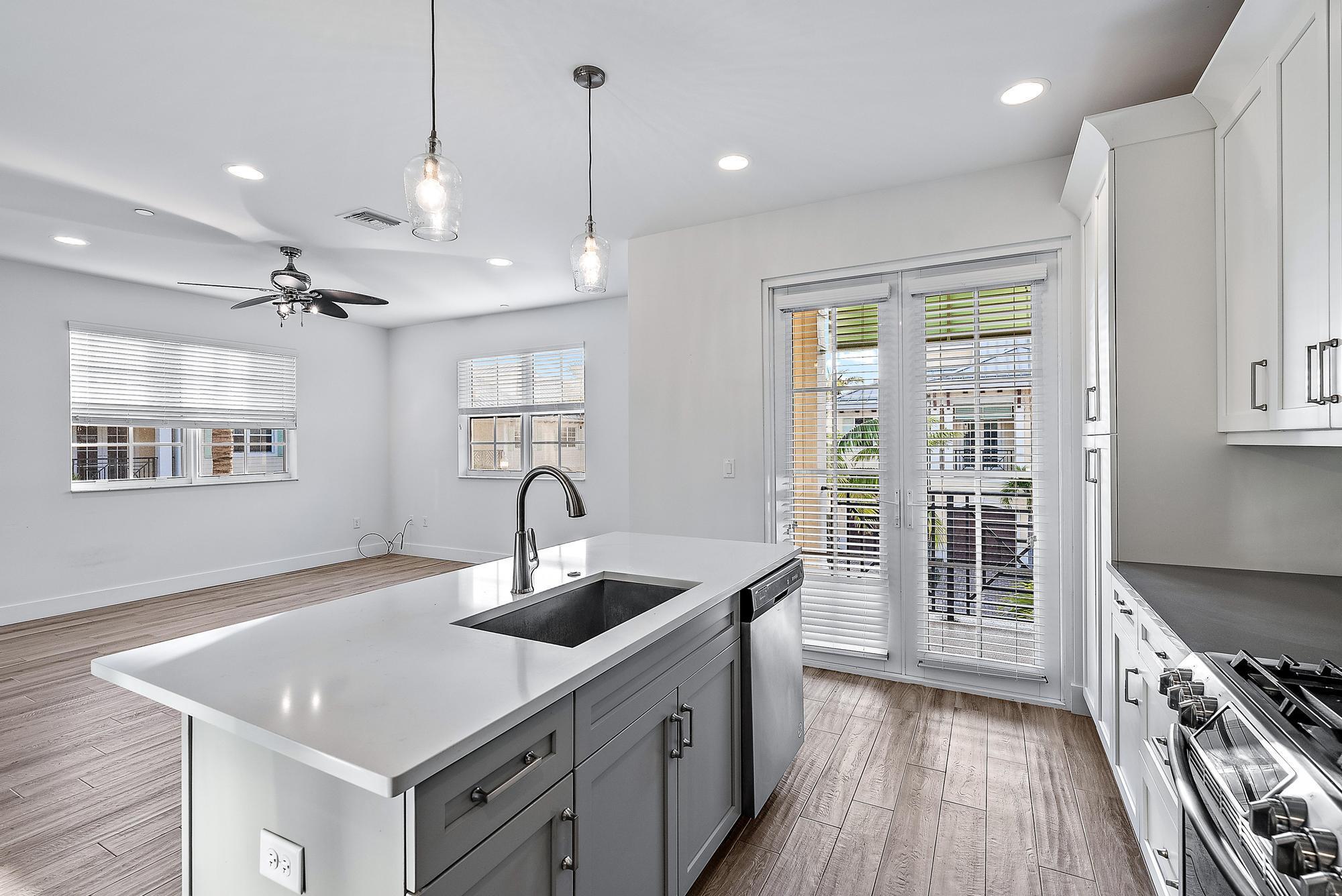 3770 County Line Road Tequesta, FL 33469 - Photo 22 of 42 a kitchen that has a sink a stove and a wooden floor
