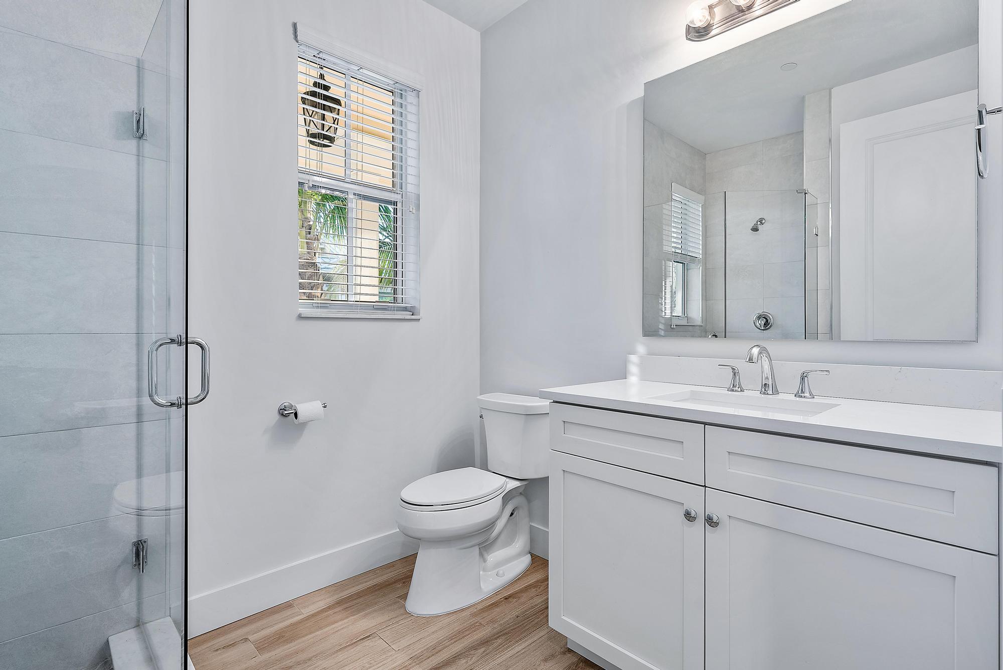 3770 County Line Road Tequesta, FL 33469 - Photo 26 of 42 a bathroom with a toilet sink a shower and vanity