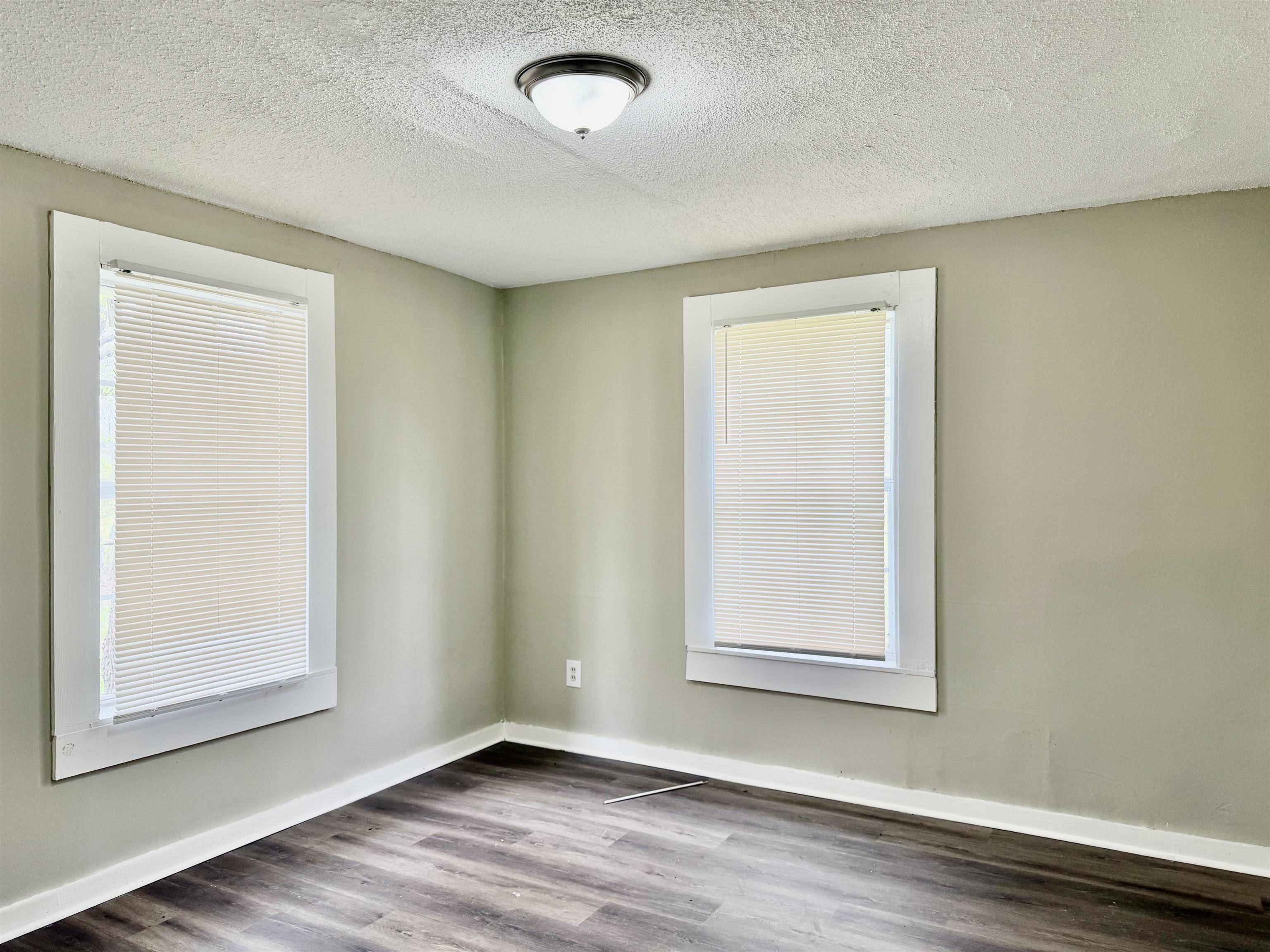1448 Menager Road Memphis, TN 38106 - Photo 7 of 17 an empty room with wooden floor and windows