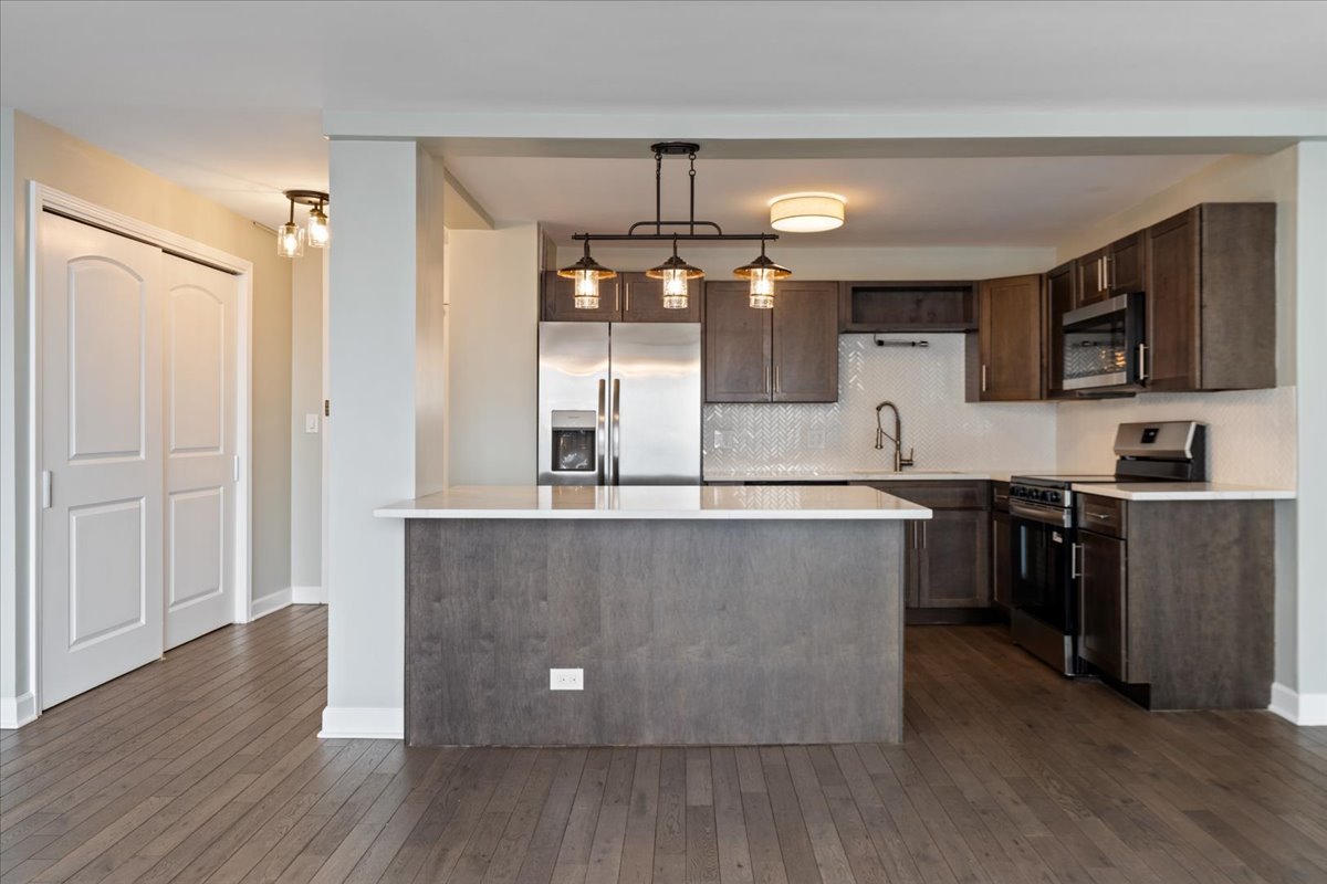 5455 North Sheridan Road, Unit 3406 Chicago, IL 60640 - Photo 13 of 30 a kitchen with kitchen island a counter top space a sink stainless steel appliances and cabinets