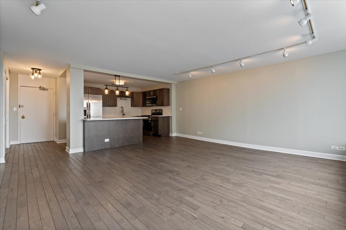 5455 North Sheridan Road, Unit 3406 Chicago, IL 60640 - Photo 8 of 30 a big room with wooden floor and kitchen view