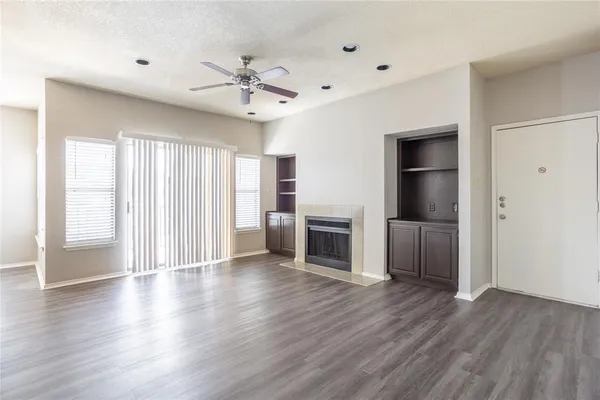 a view of a livingroom with wooden floor a ceiling fan and windows