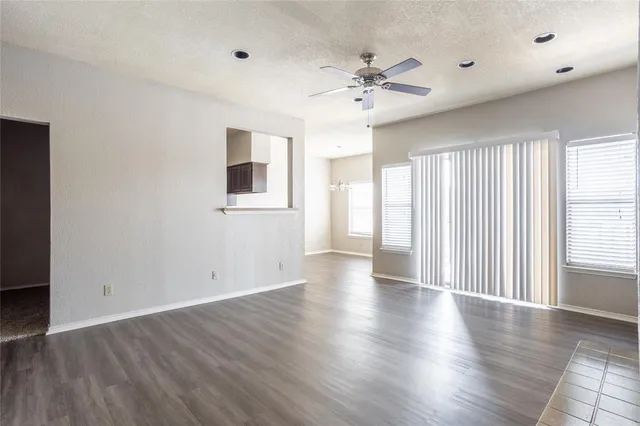 a view of an empty room with wooden floor and window