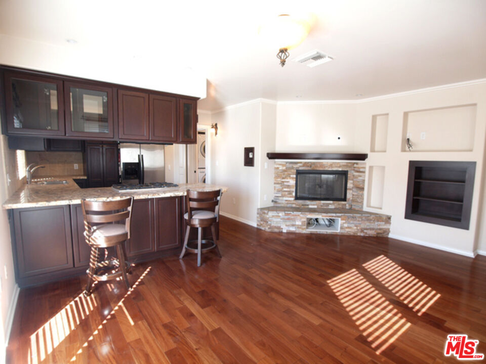1644 Hi Point Street Los Angeles, CA 90035 - Photo 1 of 11 a living room with furniture a fireplace a flat screen tv and kitchen view