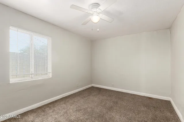 an empty room with a window and a fan