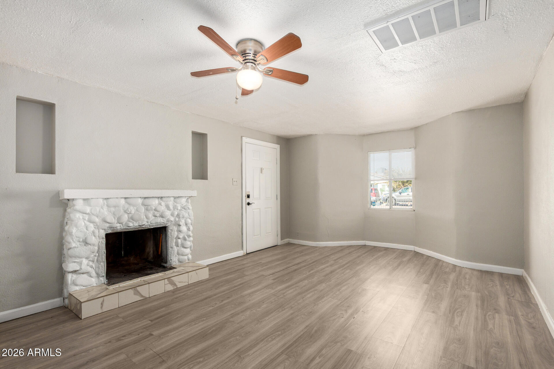 2135 West Hadley Street, Unit 1 Phoenix, AZ 85009 - Photo 5 of 18 an empty room with windows fireplace and wooden floor