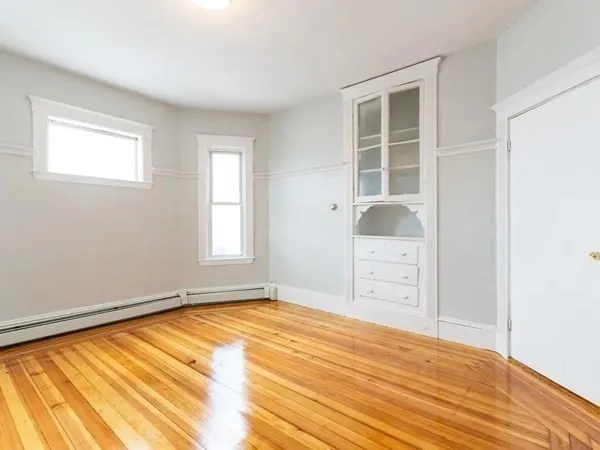 a view of empty room with window and wooden floor