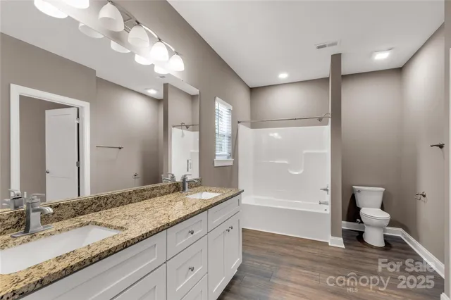 a bathroom with a granite countertop sink a toilet and a large mirror