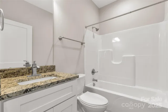 a bathroom with a granite countertop sink a toilet and shower