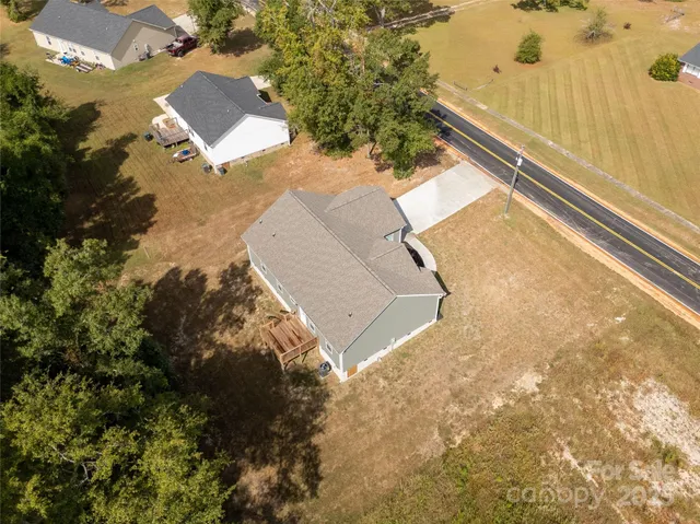 an aerial view of residential house with pool and trees all around