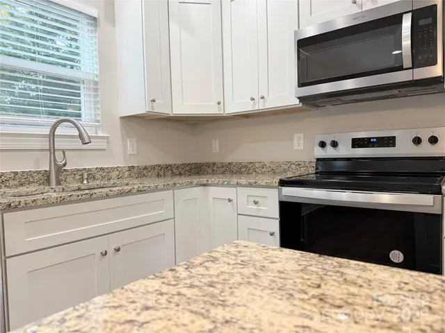 a kitchen with granite countertop a stove microwave and sink